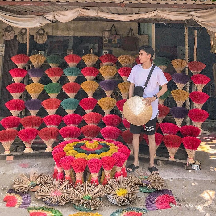 Bàn tay nghệ nhân đang nhúng phần chân hương vào thùng thuốc nhuộm màu