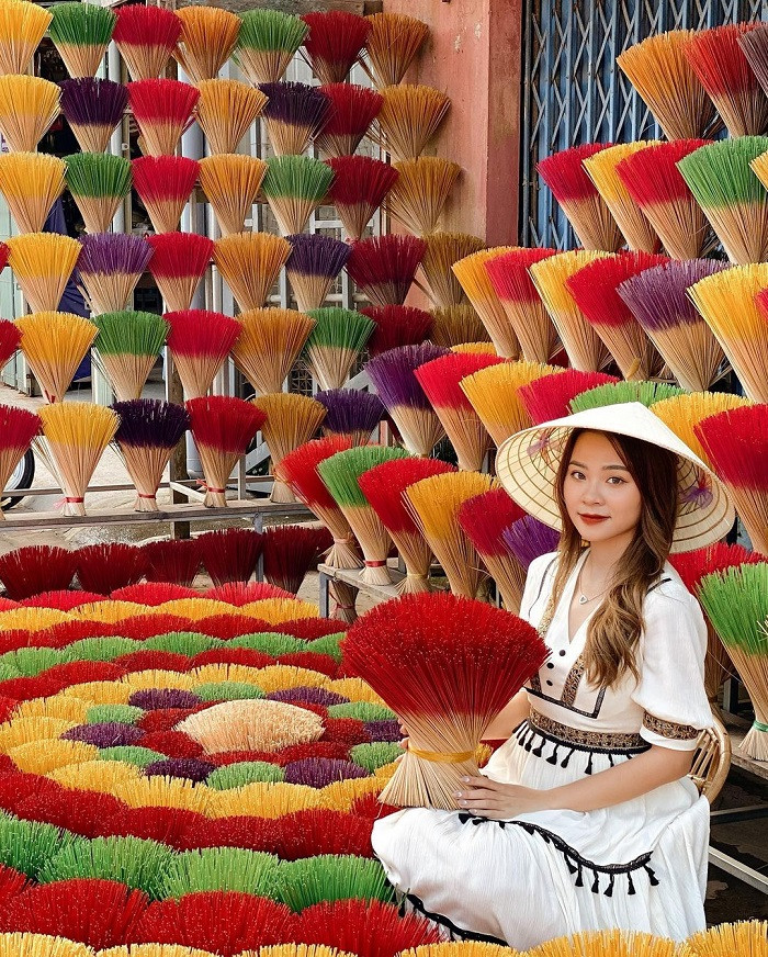 Một du khách nữ mặc áo dài truyền thống đang tạo dáng chụp ảnh giữa hàng hương rực rỡ