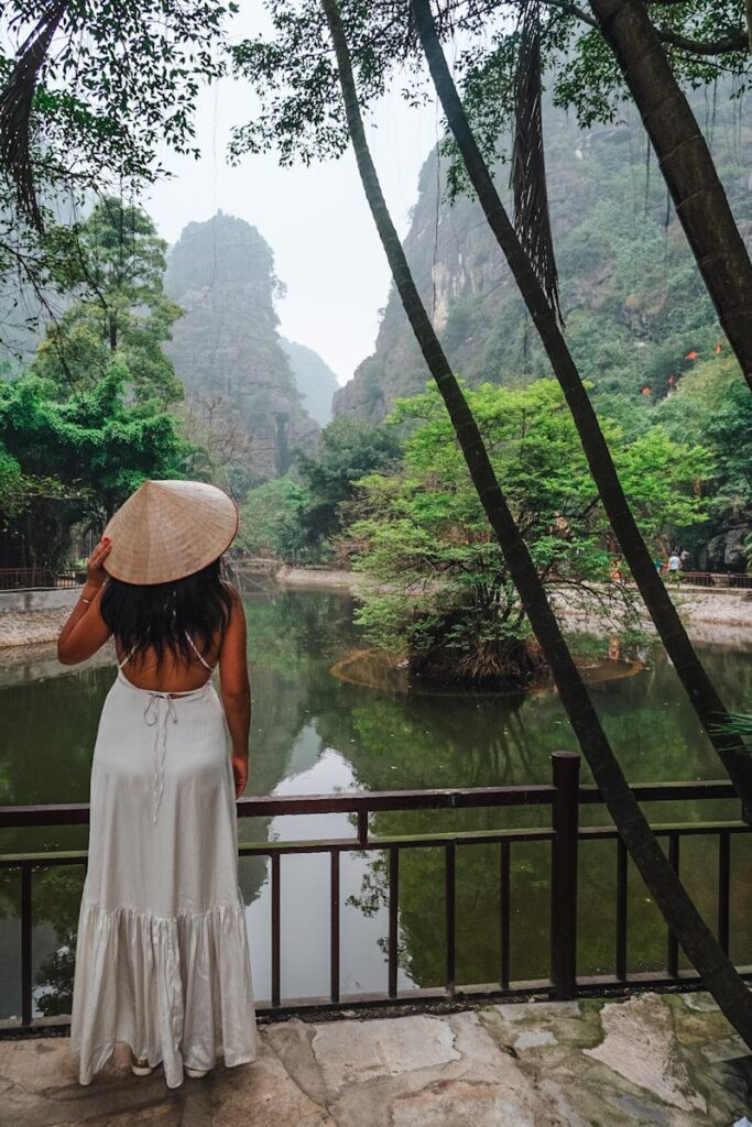 female standing in front of view of lake at the ground level of mua cave in ninh binh