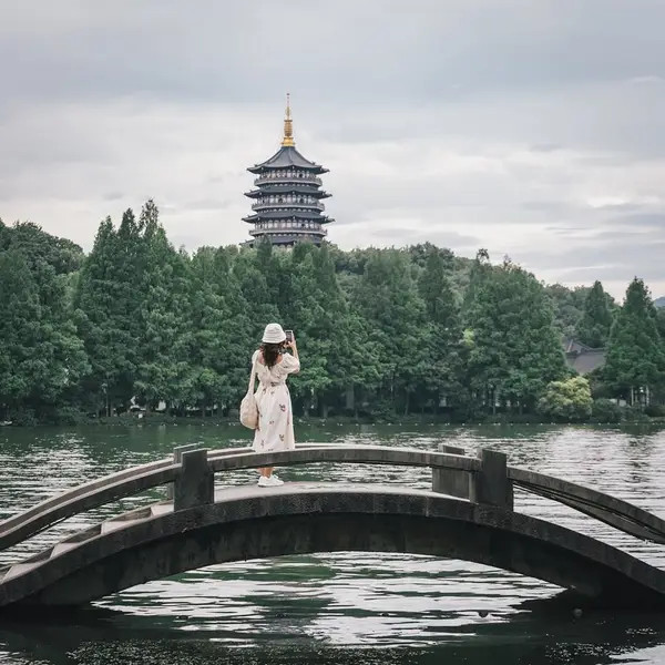 Cảnh Tây Hồ Hàng Châu yên bình với một cây cầu cổ cong cong và những cây xanh bao quanh