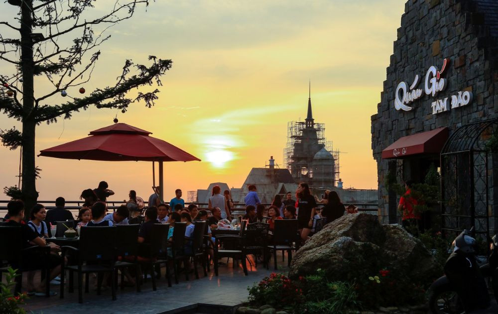 Cảnh hoàng hôn rực rỡ tại Quán Gió Tam Đảo, với bầu trời chuyển màu cam tím và thị trấn dưới thung lũng