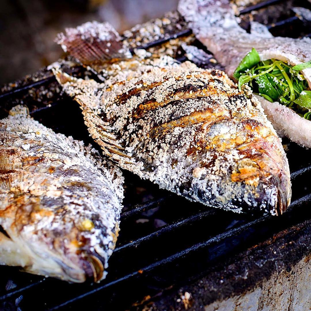 Cá nướng Pla Pao nguyên con được phủ muối và nướng trên than hồng